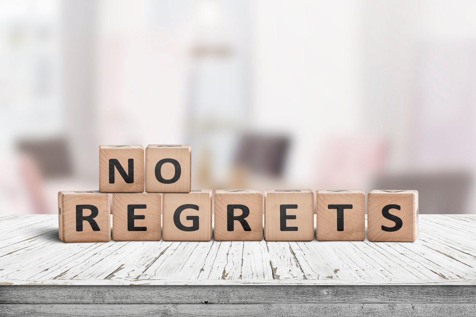 Wooden blocks spelling out the words no regrets on a rustic table