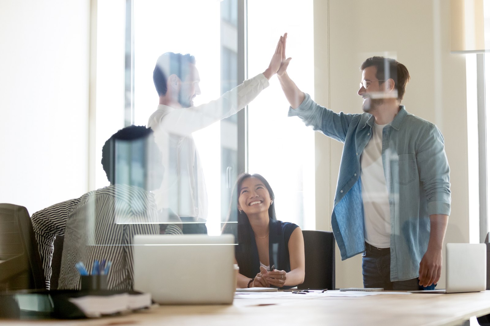 Coworkers celebrating with a high five in a bright office