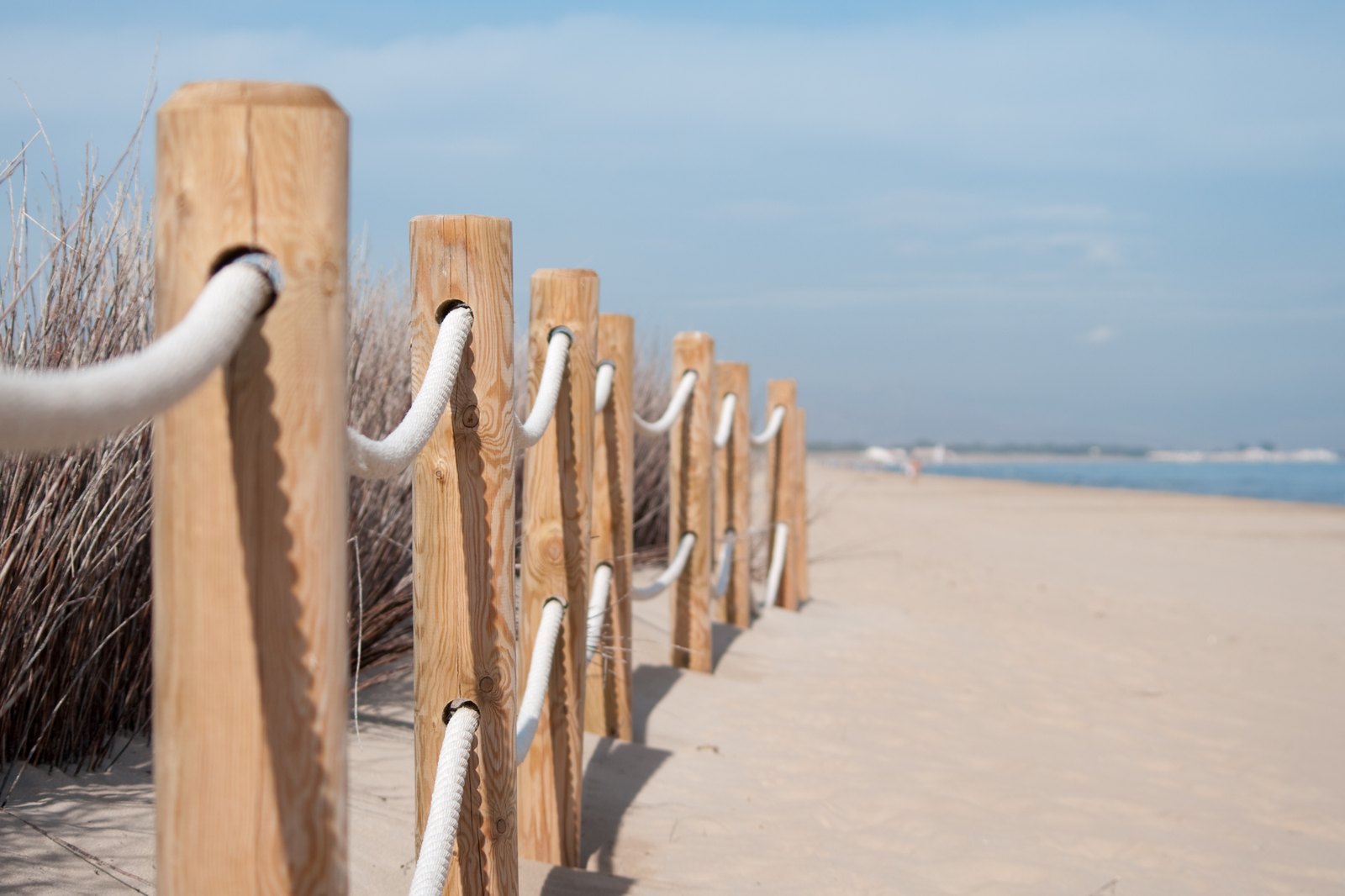 A rope fence along a quiet beach path under a clear sky